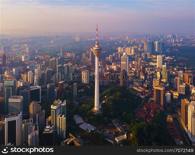 Menara Kuala Lumpur Tower with sunset sky. Aerial view of Kuala Lumpur Downtown, Malaysia. Financial district and business centers in urban city in Asia. Skyscraper and high-rise buildings at noon.