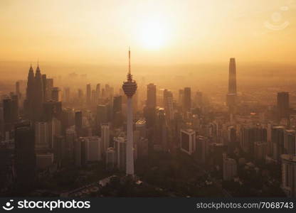 Menara Kuala Lumpur Tower with the sun. Aerial view of Kuala Lumpur Downtown, Malaysia. Financial district and business centers in urban city in Asia. Skyscraper and high-rise buildings at sunset.