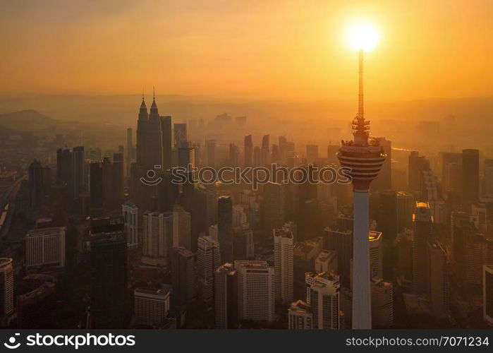 Menara Kuala Lumpur Tower with the sun. Aerial view of Kuala Lumpur Downtown, Malaysia. Financial district and business centers in urban city in Asia. Skyscraper and high-rise buildings at sunset.