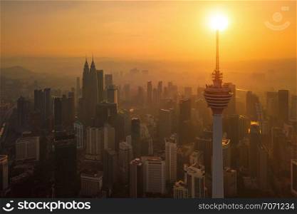 Menara Kuala Lumpur Tower with the sun. Aerial view of Kuala Lumpur Downtown, Malaysia. Financial district and business centers in urban city in Asia. Skyscraper and high-rise buildings at sunset.
