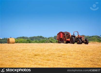 Menorca combine tractor wheat with round bales in golden field