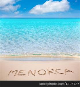 Menorca word written on sand of mediterranean beach with turquoise waters