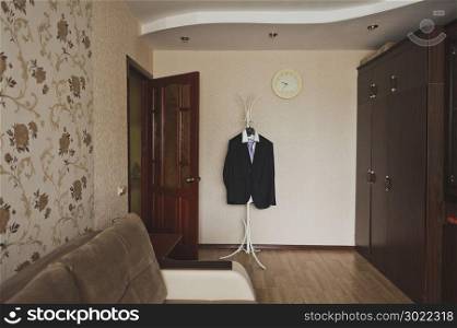 Mens suit on a hanger in the middle of the room.. Strict male costume on a hanger in the room waiting for the master 595.