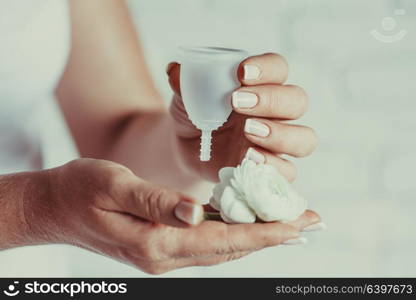 Menstrual cup in female hands. Woman holds flower and silicone hygiene cup, new device for minimize waste and preservation of the environment. menstrual cup in female hands