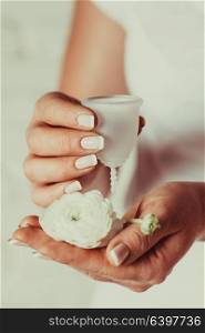 Menstrual cup in female hands. Woman holds flower and silicone hygiene cup, new device for minimize waste and preservation of the environment. menstrual cup in female hands