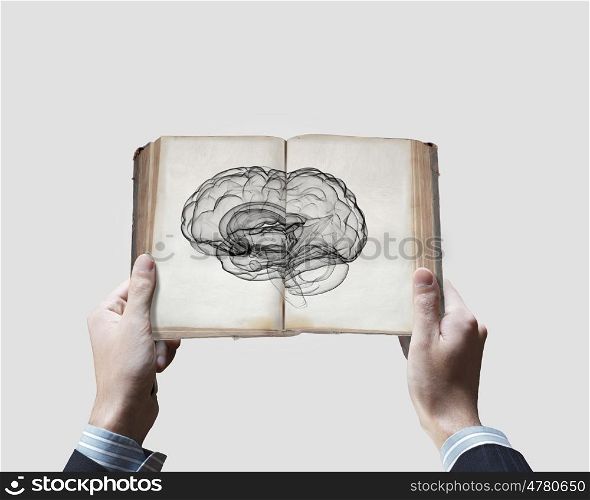 Mental ability. Close up of male hands holding opened book with brain picture