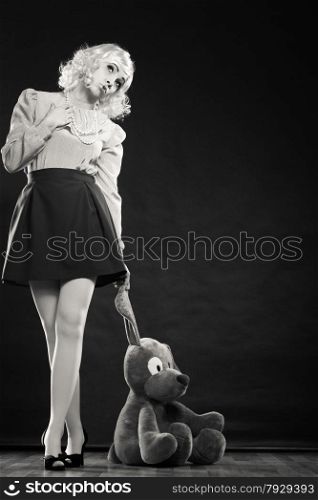 Mental disorder concept. Young childlike woman wearing like puppet doll and big dog toy standing black and white photo