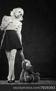 Mental disorder concept. Young childlike woman wearing like puppet doll and big dog toy standing black and white photo