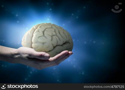 Mental health concept. Close up of human hand holding brain