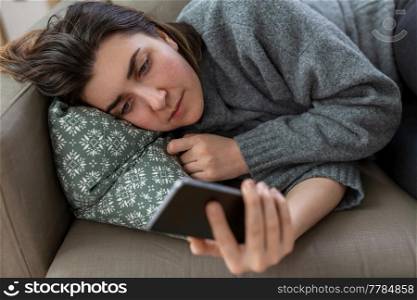 mental health, psychological help and depression concept - stressed woman with smartphone lying on sofa at home. stressed woman with smartphone on sofa at home
