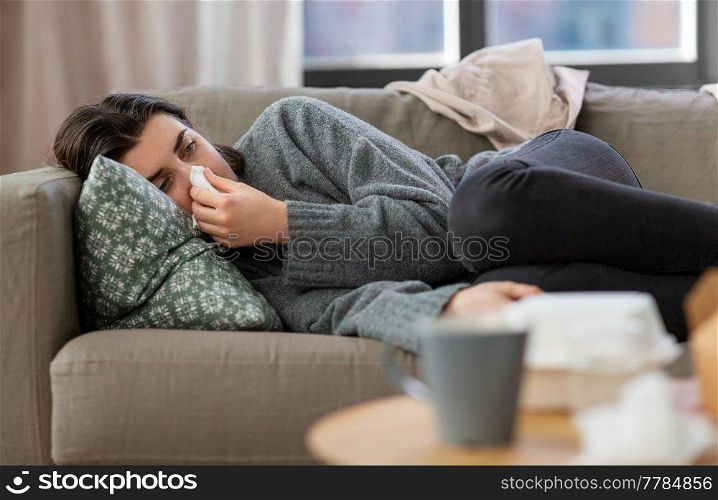 mental health, psychological problem and depression concept - sad crying woman with paper tissue lying on sofa at home. sad crying woman with tissue lying on sofa at home
