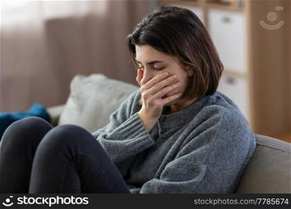mental health, psychological problem and depression concept - stressed woman sitting on sofa at home. stressed woman sitting on sofa at home