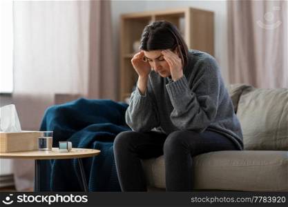 mental health, psychological problem and depression concept - stressed woman with sedative medicine or painkiller on table having headache at home. stressed woman with medicine having headache