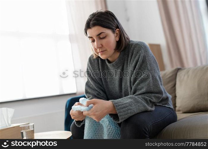 mental health, stress and depression - sad woman popping bubble wrap at home. sad woman popping bubble wrap at home