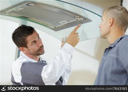 mentor and young male repairman checking kitchen extractor filter