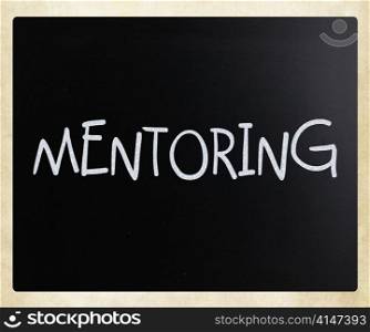""Mentoring" handwritten with white chalk on a blackboard"