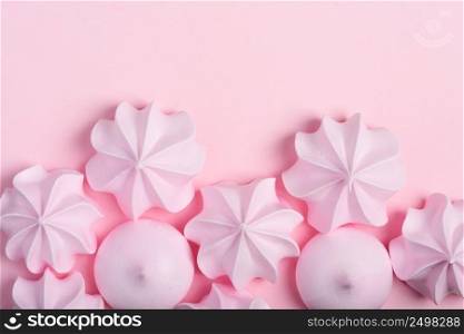 Meringue cookies border. Sweet crispy twisted and drop meringue on pink pastel background with copy-space.