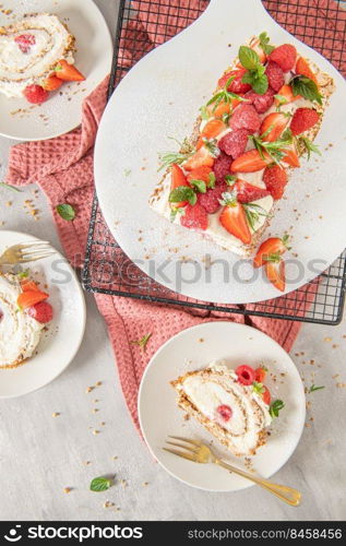 Meringue roll with a gentle airy cream, crunchy peanut, mint, rosemary and filling with raspberries and strawberries. Pavlova summer sweet dessert