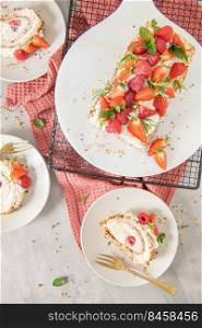 Meringue roll with a gentle airy cream, crunchy peanut, mint, rosemary and filling with raspberries and strawberries. Pavlova summer sweet dessert