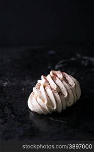 Meringues with cocoa powder on dark background, selective focus, copy space