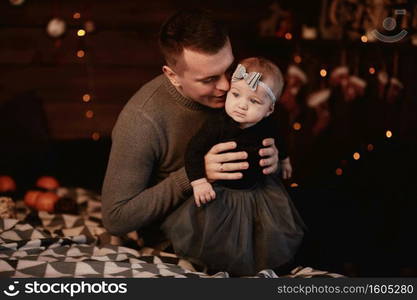 Merry Christmas and Happy Holidays. Cheerful father hugging cute baby daughter girl on bed near Christmas background. Dad and little child having fun and playing together at home. Merry Christmas and Happy Holidays. Cheerful father hugging cute baby daughter girl on bed near Christmas background. Dad and little child having fun and playing together at home.