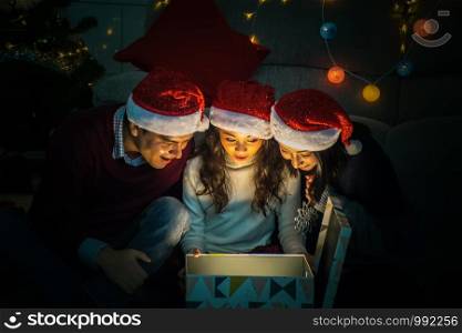 Merry Christmas and Happy Holidays.Happy family opens the magic box with light in dark on Christmas day at home.Christmas family .