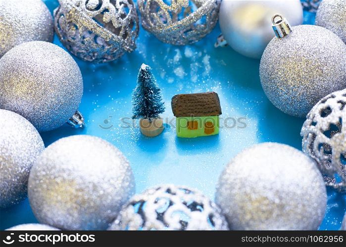 Merry Christmas and Happy Holidays, Miniature house with christmas baubles decoration on blue background.