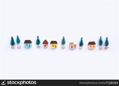 Merry Christmas and Happy Holidays, Miniature house with fir trees on white background. Copy space