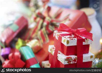 Merry Christmas background concept. Closeup of red gift box with blurred another gift boxes in background.