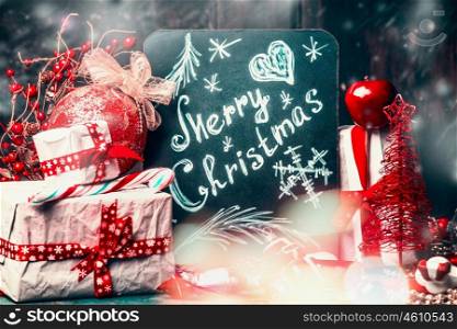 Merry Christmas card lettering drawn on back chalkboard with handmade gift with red holiday decoration and snow