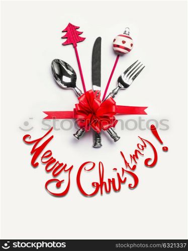 Merry Christmas card with table place setting with cutlery, red ribbon and text lettering on white desk background, top view. Layout for holiday greeting, festive dinner invitation