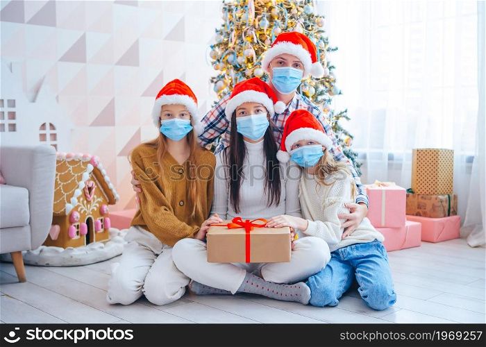 Merry Christmas. Family of four with gifts on Christmas. Parents and kids are wearing facemasks. Happy young family with kids holding christmas presents