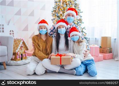 Merry Christmas. Family of four with gifts on Christmas. Parents and kids are wearing facemasks. Happy young family with kids holding christmas presents
