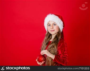 Merry Christmas, happy attractive girl in Santa?s hat on bright red bright color background. Portrait of a beautiful girl in anticipation of the New Year. Copy space.. Portrait of a beautiful girl in anticipation of the New Year. Copy space.