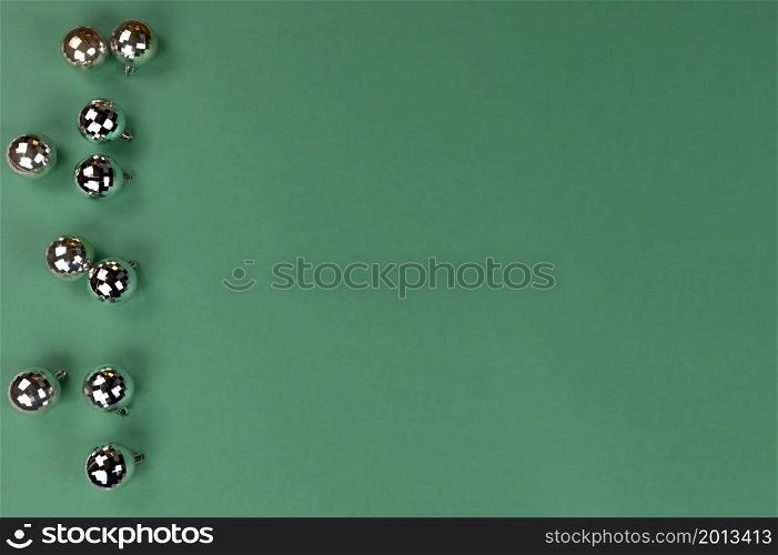 Merry Christmas or Happy New Year holiday concept with shiny ornament ball decorations on green background in flat lay format