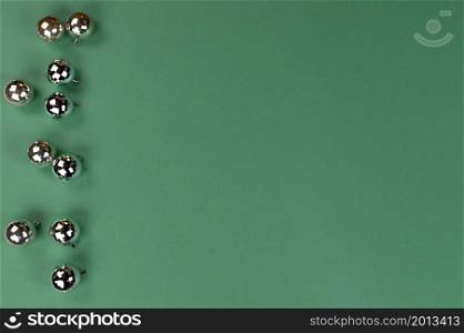 Merry Christmas or Happy New Year holiday concept with shiny ornament ball decorations on green background in flat lay format