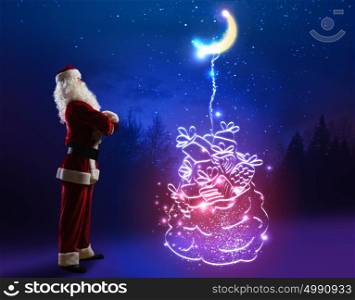 Merry Christmas. Santa Claus with big bag of gifts against night background