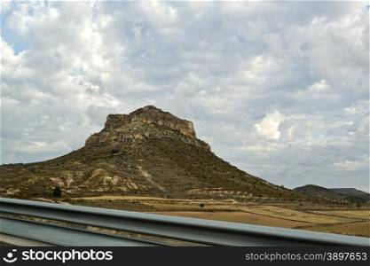 Mesa in the arid central Spain country seen from the highway. Mesas are elevated areas of land with a flat top and sides that are usually steep cliffs, formed by weathering and erosion of horizontally layered rocks.