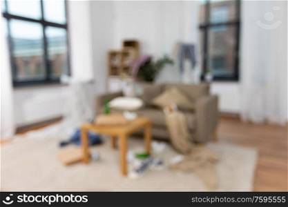 mess, disorder and interior concept - blurred photo of messy home living room with scattered stuff. interior of messy home room with scattered stuff