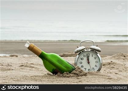 message in bottle on the beach with alarm clock