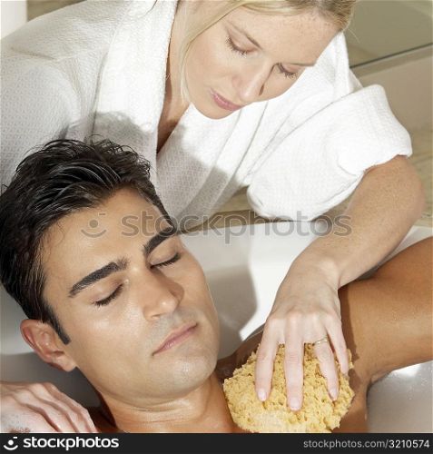 Message therapist rubbing a bath sponge on a young man&acute;s body