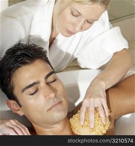 Message therapist rubbing a bath sponge on a young man&acute;s body