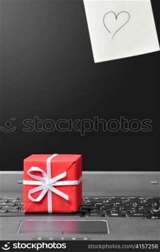 message with heart on sticky note red gift box on a laptop keyboard