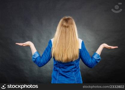 Messages and new information concept. Back rear view of blonde young casual woman. Girl showing presenting copy space.. Back view of woman showing copy space.