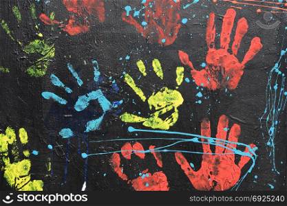 Messy handprints and dripping paint on textured wall background. Colorful hand imprints abstract pattern.