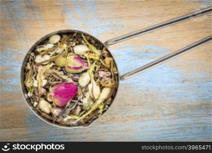 Mesuring scoop of healthy skin herbal tea, a blend of red rose bud. peach flower, lavender, rosemary, honeysuckle