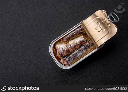 Metal aluminum can of canned sardines in oil with spices and salt on a dark concrete background