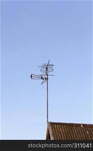metal antenna for receiving a television signal installed on the roof of a private house, against a blue sky. Television Antenna roof.