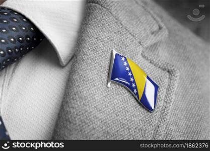 Metal badge with the flag of Bosnia and Herzegovina on a suit lapel.. Metal badge with the flag of Bosnia and Herzegovina on a suit lapel