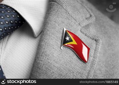 Metal badge with the flag of East Timor on a suit lapel.. Metal badge with the flag of East Timor on a suit lapel